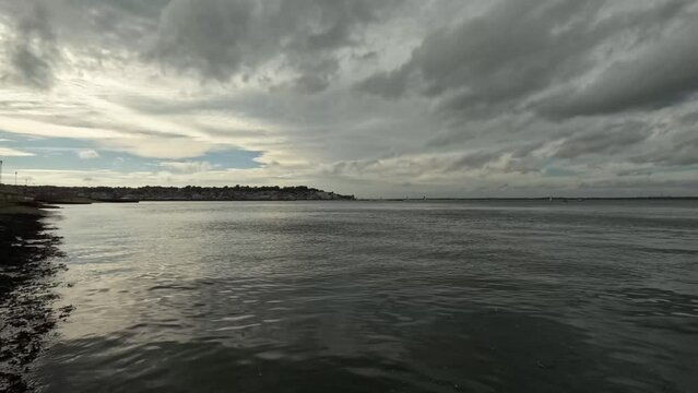 Timelapse, waves and clouds in a beach on the Isle of Wight with a boat in the background.