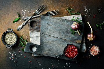 Obraz na płótnie Canvas Cutting board, rosemary and spices. On a dark slate background. Free space for the recipe.