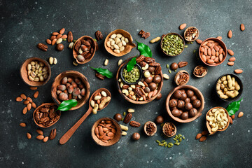 peeled and shelled nuts in wooden bowls. Top view. On a dark background.