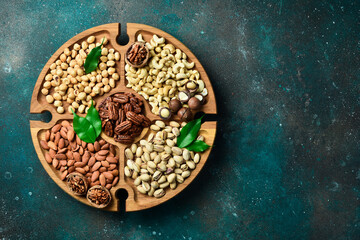 Assortment of nuts on a wooden plate. Top view. Mixed nuts on wooden table. On a dark background.