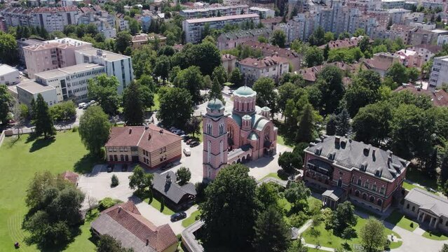 Aerial view circling Orthodox Christian Church of Holy Trinity looking down over green domed rooftop in Banja Luka district