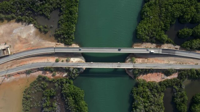 A pedestal footage as the drone moves to a higher elevation revealing two bridges with vehicles moving, the mangrove forests and this estuarine body of water, Porlamar, Margarita Island, Venezuela.