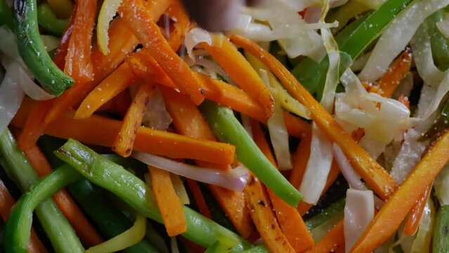 adding salt with hand to the vegetable stir fry cooking