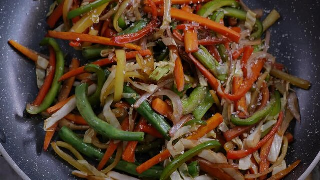 adding suger with hand to the vegetable stir fry cooking in a non stick fry pan