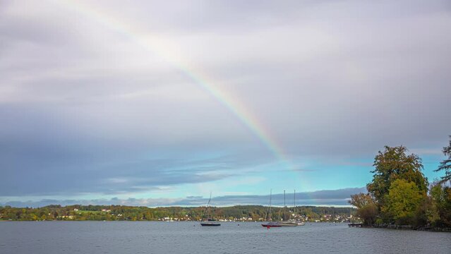 Rainbow over lake Attersee with boats, time lapse view