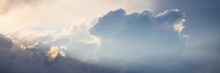 Beautiful sky background with clouds and sunbeams. Dramatic cloudscape with sun rays. Wide...