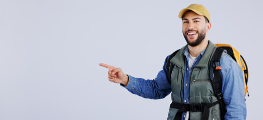 Happy man, backpack and pointing on mockup for travel, adventure or hiking tips against a studio...