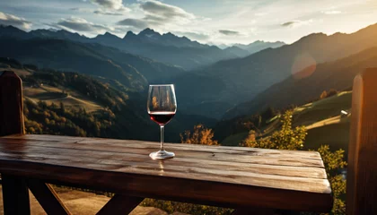 Fotobehang a glass of red wine on a table in front of a mountain range © msroster