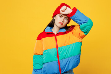 Young sad sick ill tired woman she wearing padded windbreaker jacket red hat casual clothes put hand on forehead looking camera isolated on plain yellow background studio portrait. Lifestyle concept. © ViDi Studio