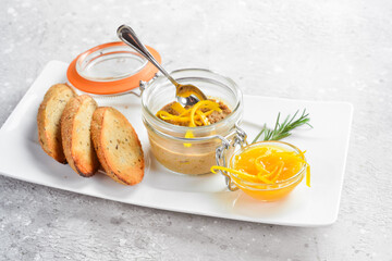 Liver pate. Pate with toast in a glass jar. On a white plate. On a gray stone background....