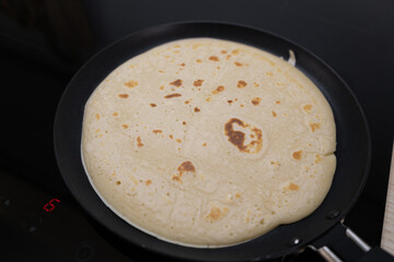 Making pancakes or crepes on a frying pan. Delicious meal preparation, cooking thin pancake.