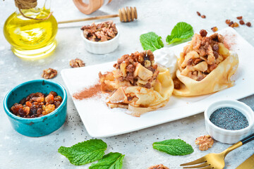 Dessert. Pancakes with apples, nuts, raisins and ice cream. On a white plate. On a gray stone background. Restaurant menu.