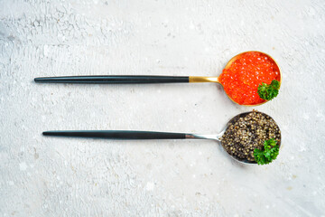 Caviar in a spoon. Set of black and red caviar in metal spoons. Gourmet food in a restaurant. On...