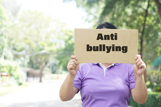 Paper placard with text Anti bullying, was held by a women, stands outside. Concept, campaign for calling everybody to stop bullying each other by using bad word, action, texting or online.         