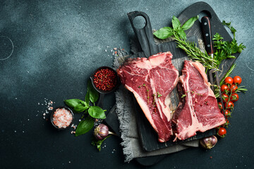 Two Raw T-bone Steak with fresh herbs and ready to cook. A piece of veal. - obrazy, fototapety, plakaty