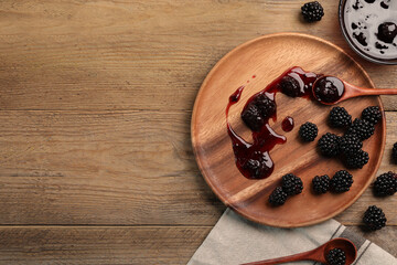 Tasty blackberry jam and fresh berries on wooden table, flat lay. Space for text