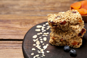 Stack of tasty granola bars on wooden table, closeup. Space for text