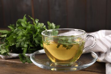 Aromatic herbal tea with parsley on wooden table, closeup