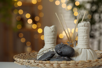 Spa composition. Herbal bags, stones, reed diffuser and dry lavender flowers on table indoors, bokeh effect