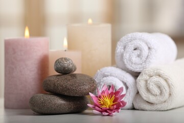 Fototapeta na wymiar Spa composition. Burning candles, lotus flower, stones and towels on white table