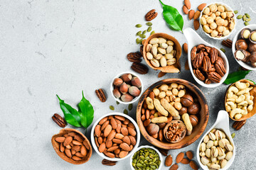 Assortment of nuts in bowls. Cashew, hazelnuts, walnuts, pistachio, pecans, pine nuts, peanut. Food mix background, top view, copy space.