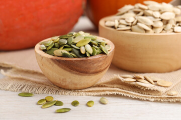 Bowls with pumpkin seeds on light wooden table