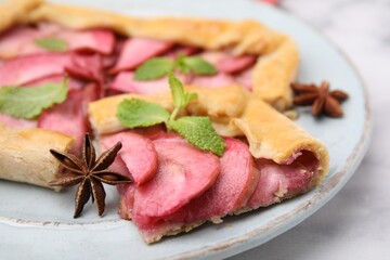 Delicious apple galette with mint and star anise on white marble table, closeup