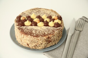 Delicious Kyiv Cake decorated with cream and hazelnuts on white table