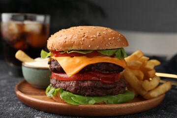 Tasty cheeseburger with patties, sauce and French fries on grey textured table, closeup