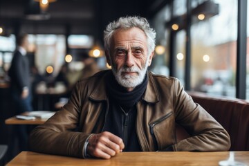 Portrait of senior man sitting at table in cafe and looking at camera