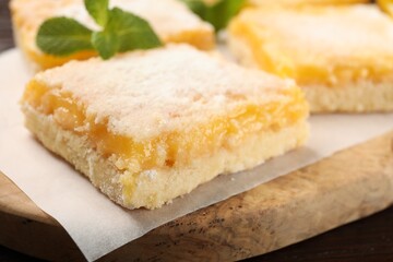 Tasty lemon bar with powdered sugar and mint on board, closeup