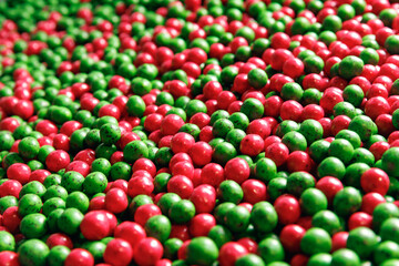 Closeup red and green color dragee, chocolate covered nuts, sweet candy background