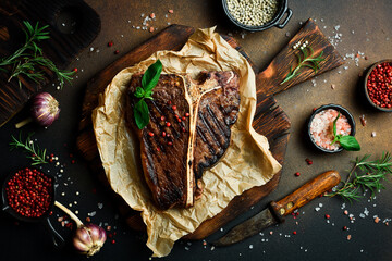 T-bone steak with rosemary on parchment paper. Beef steak on a dark background. Meat.