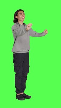 Side view of asian man acting as choir director for musical show, moving hands like a choirmaster chief over greenscreen backdrop. Male person conducting band to sing, smiling choirmaster musician.