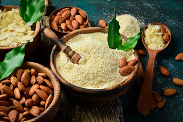 Wooden bowl with almond flour and nuts. On a dark background. Top view. Copy space.