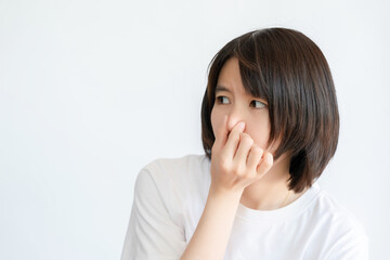 Asian woman with short hair covers her nose with her hand because something smells bad.