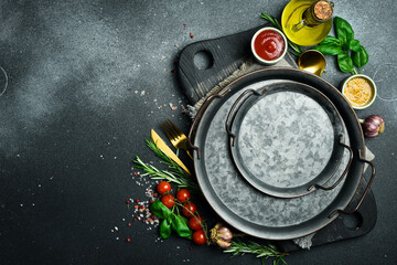 Kitchen banner. A kitchen table on which vegetables, spices and a metal tray are laid out. On a dark stone background. free space for text. - obrazy, fototapety, plakaty