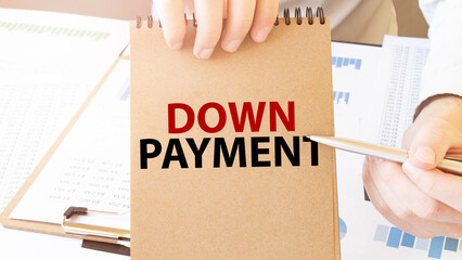 Text DOWN PAYMENT on brown paper notepad in businessman hands on the table with diagram. Business...