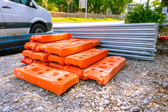 Stack of metal fence and pile of plastic foot stabilizers at the construction site