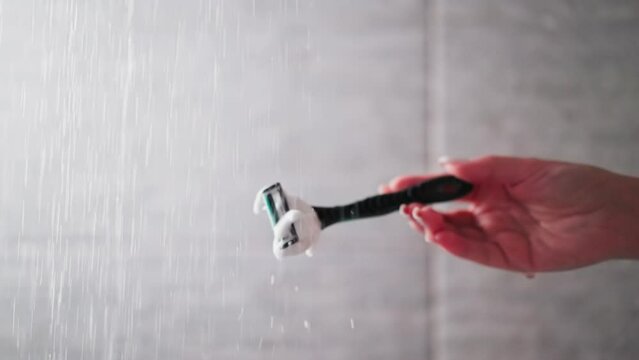 Woman cleans razor from foam in shower sprays