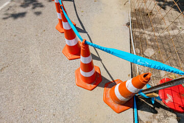 Few traffic cones tied, connected, with blue warning tape