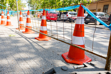 Plastic foot stabilizer for metal mobile wire fence at the construction site with warning traffic cones
