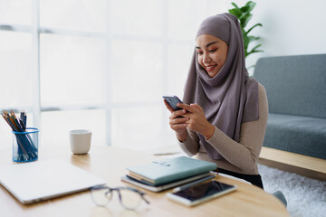 Obraz premium Muslim undergraduate student using mobile phone to contact friends.