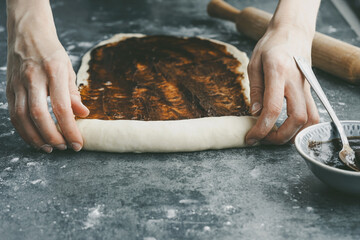 Rolls out the dough with a rolling pin a on concrete table. The process of preparing dough...