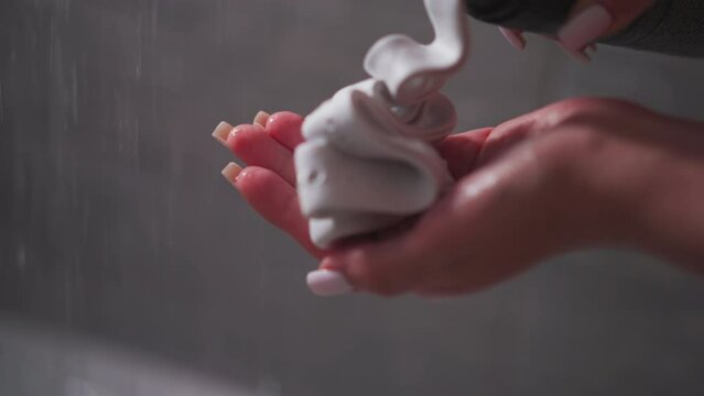 Woman pumps shaving foam on palm in bathroom