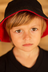 thoughtful handsome boy of 5 years old in a black hat and jacket with a yellow background