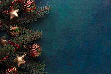 Fir branch with Christmas decoration on a  dark blue-green painted wooden background.  Flat lay. ...