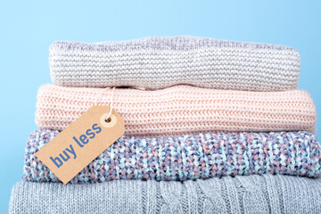 Stack of winter sweaters with the buy less tag. Conscious consumption. Environmental friendliness...