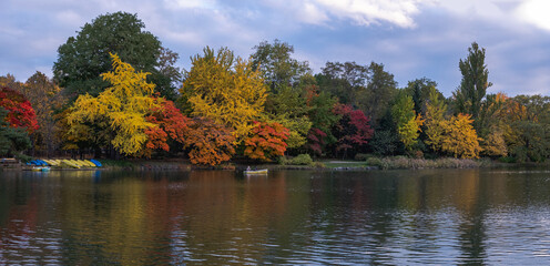 A beautiful autumn scene with a small lake surrounded by colorful trees and foliage.