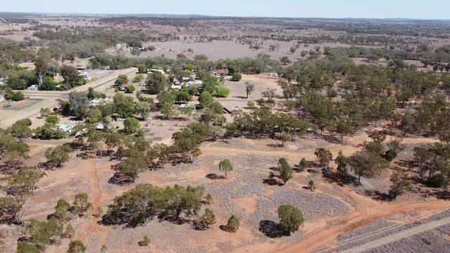 Drone flying over bush land towards a very small town in the Australian outback